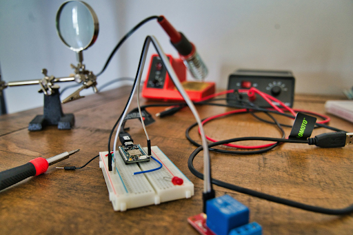 Electronics testing workstation with circuit board on breadboard, multimeter probes, and diagnostic equipment used for integrated product safety testing, compliance validation, and reliability analysis in high-stakes manufacturing environments.