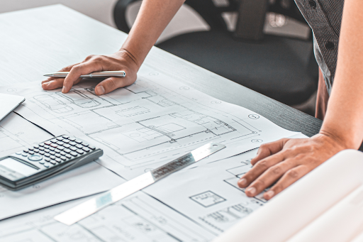 Close-up of an engineer analyzing technical drawings and measurements on a workspace, representing custom design and engineering processes for packaging or storage solutions