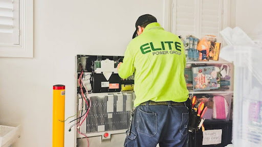 A technician working on the installation of a lithium battery energy storage system in an indoor commercial setting, illustrating the technical complexity of on-site battery storage and the importance of fire code lithium battery storage regulations in commercial operations.