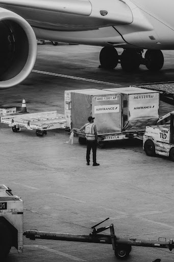 Airport ground crew load cargo onto an aircraft, representing the air transport conditions covered by the 2026 lithium and sodium-ion battery shipping regulation updates.