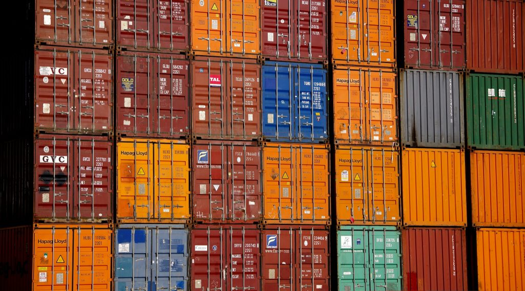 Stacked shipping containers at a multimodal port terminal, representing the regional coordination and supplier oversight required to scale a lithium battery safety program across global operations.